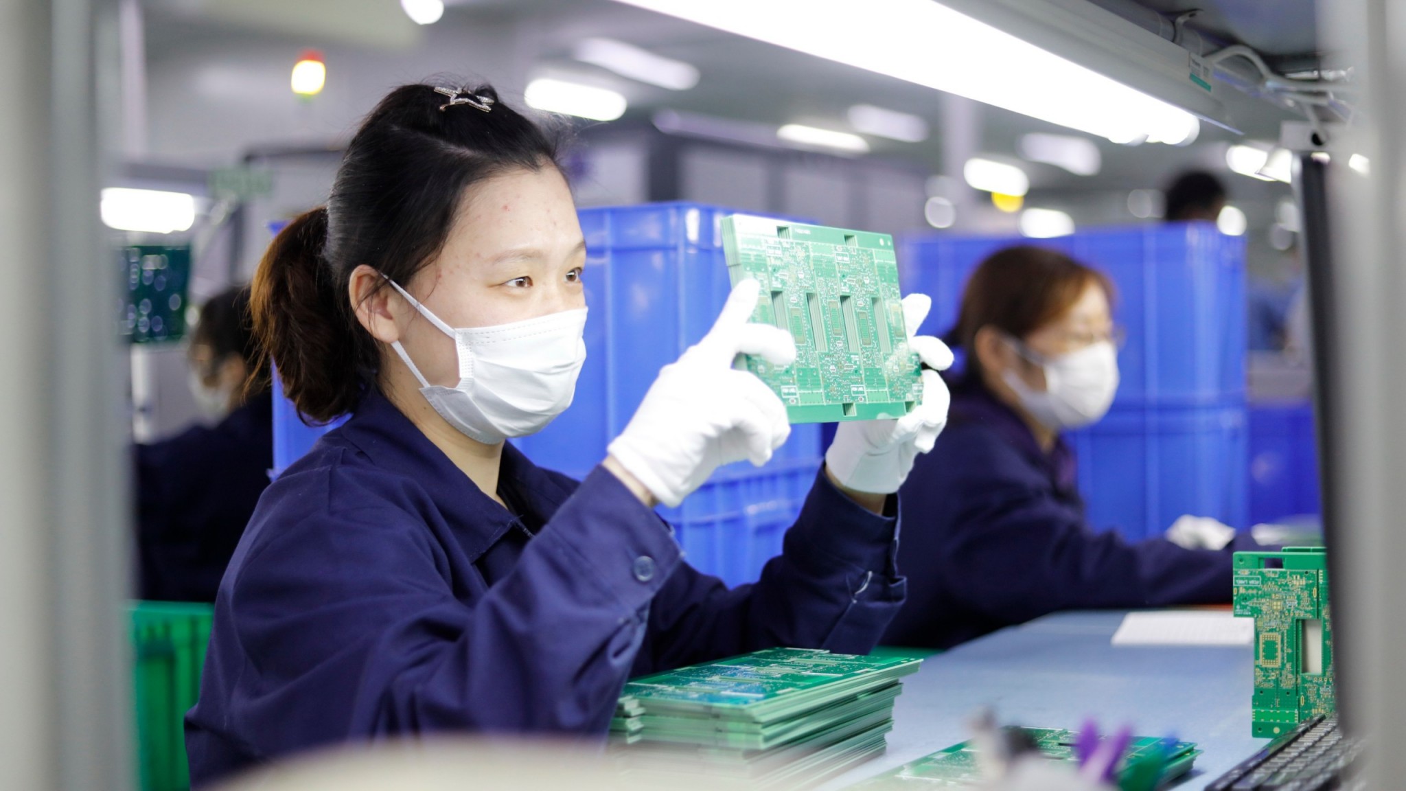 Chinese workers wear masks to produce circuit boards in a factory