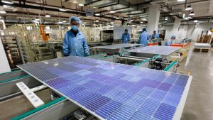 shutterstock_1891732567 Workers operate equipment to produce photovoltaic circuit boards at a production workshop of a green energy technology company